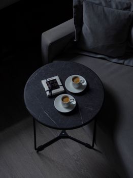Two espresso cups on a table beside a sofa create a cozy vibe.