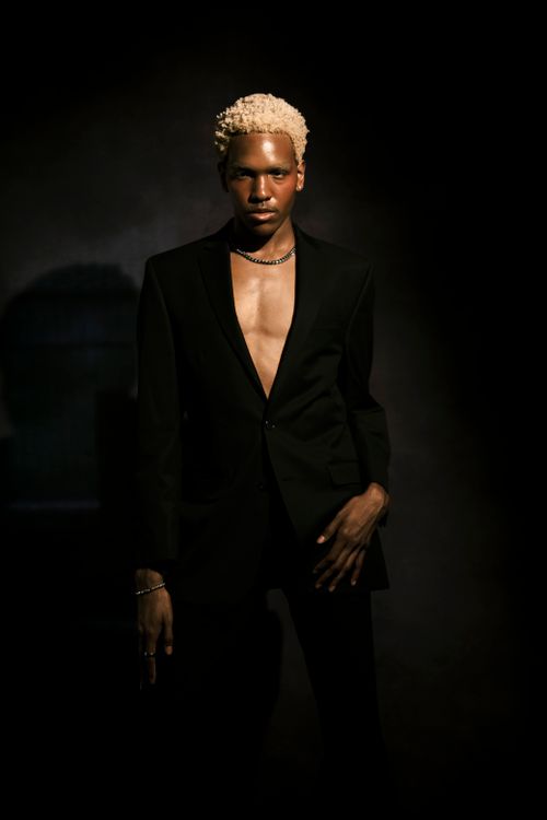 Free Elegant portrait of a male fashion model posing in a dark suit in studio lighting Stock Photo