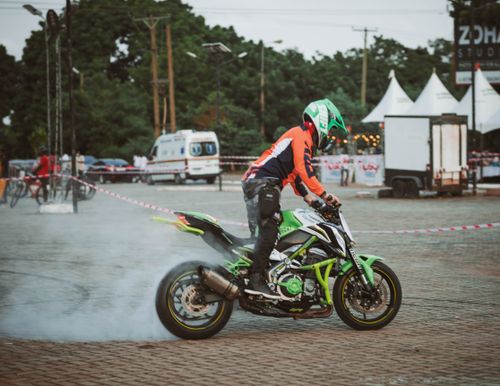 Free Stunt rider performing a burnout on a motorcycle in Accra, Ghana. Stock Photo