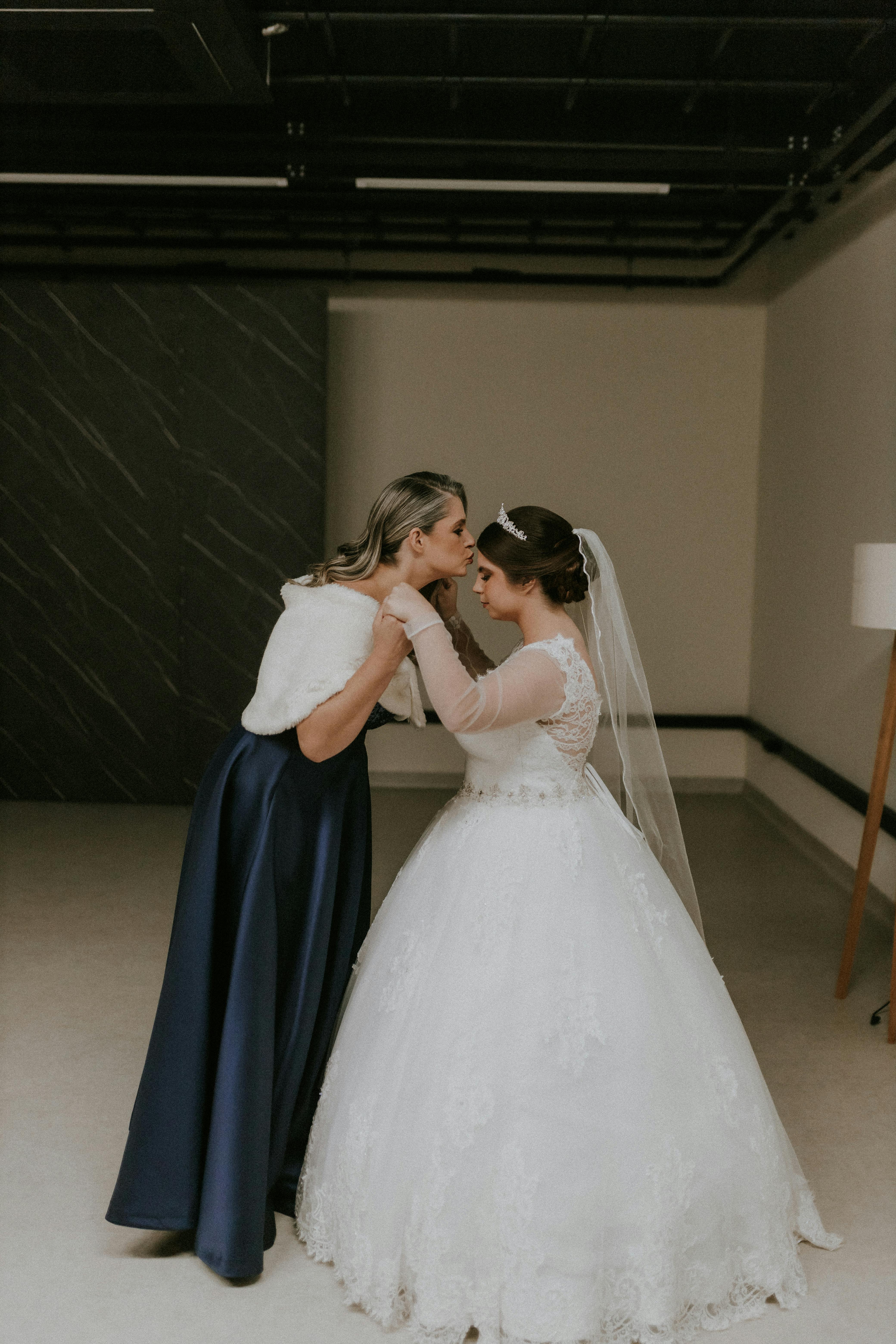 mother in dress kissing bride