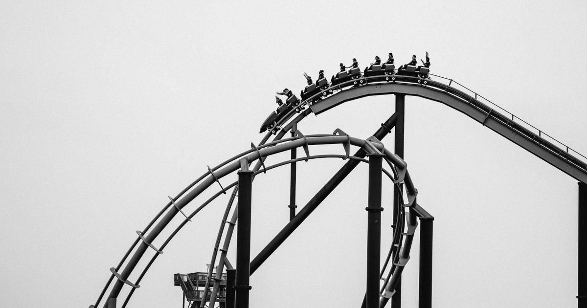 People riding a roller coaster, representing the cycle of market emotions traders move through
