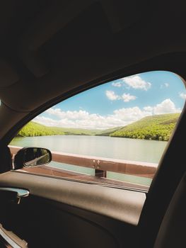 Peaceful view of a lake and hills from a car window. Ideal travel escape snapshot.