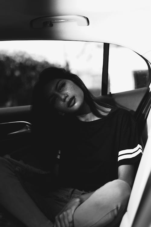 Monochrome Photo of Woman Sitting in Vehicle