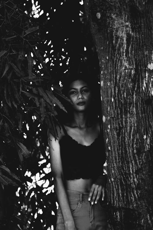 Monochrome Photo of Woman Wearing Crop Top While Standing Beside Tree