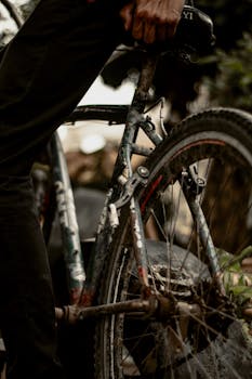 Close-up of an old bicycle with a rider, highlighting rusty textures and urban grit.