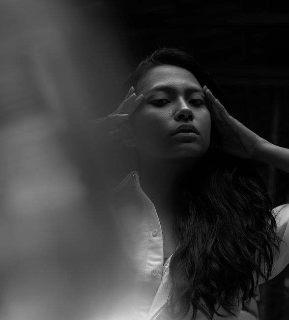 Elegant black and white portrait showcasing a woman with a contemplative pose and fashionable attire.
