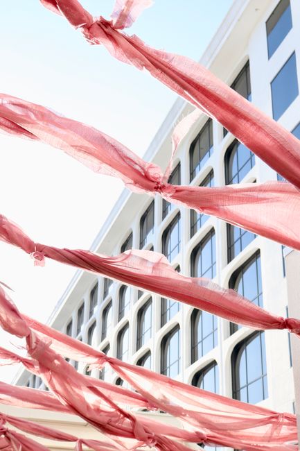Bright pink fabric decorates a modern building facade, creating a vibrant outdoor scene.