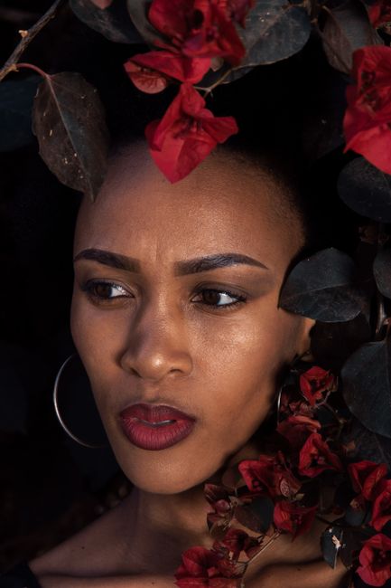 Elegant portrait of a woman surrounded by vibrant red Bougainvillea.
