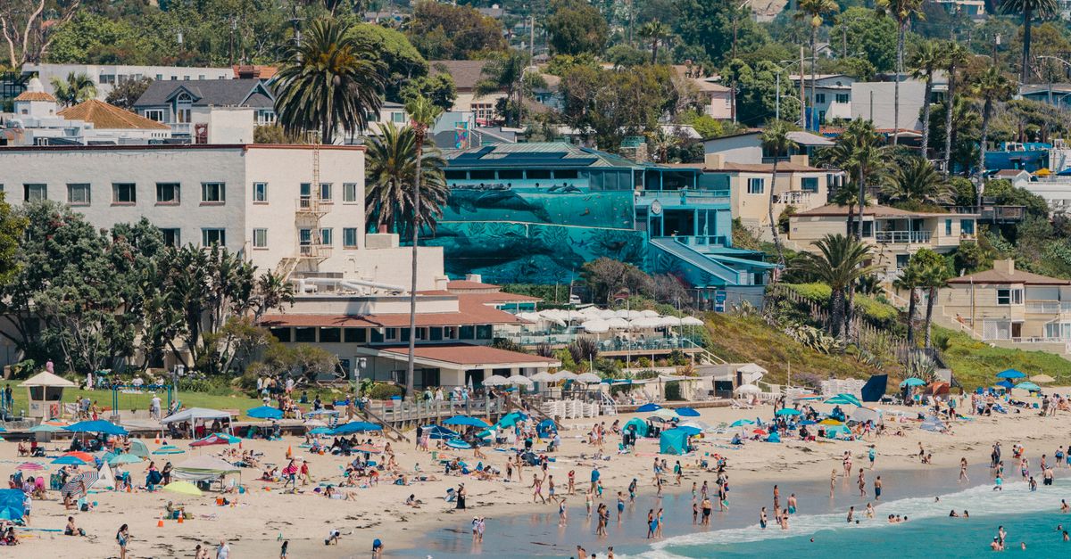 A vibrant beach scene at Laguna Beach, CA, with tourists enjoying the sunny day.