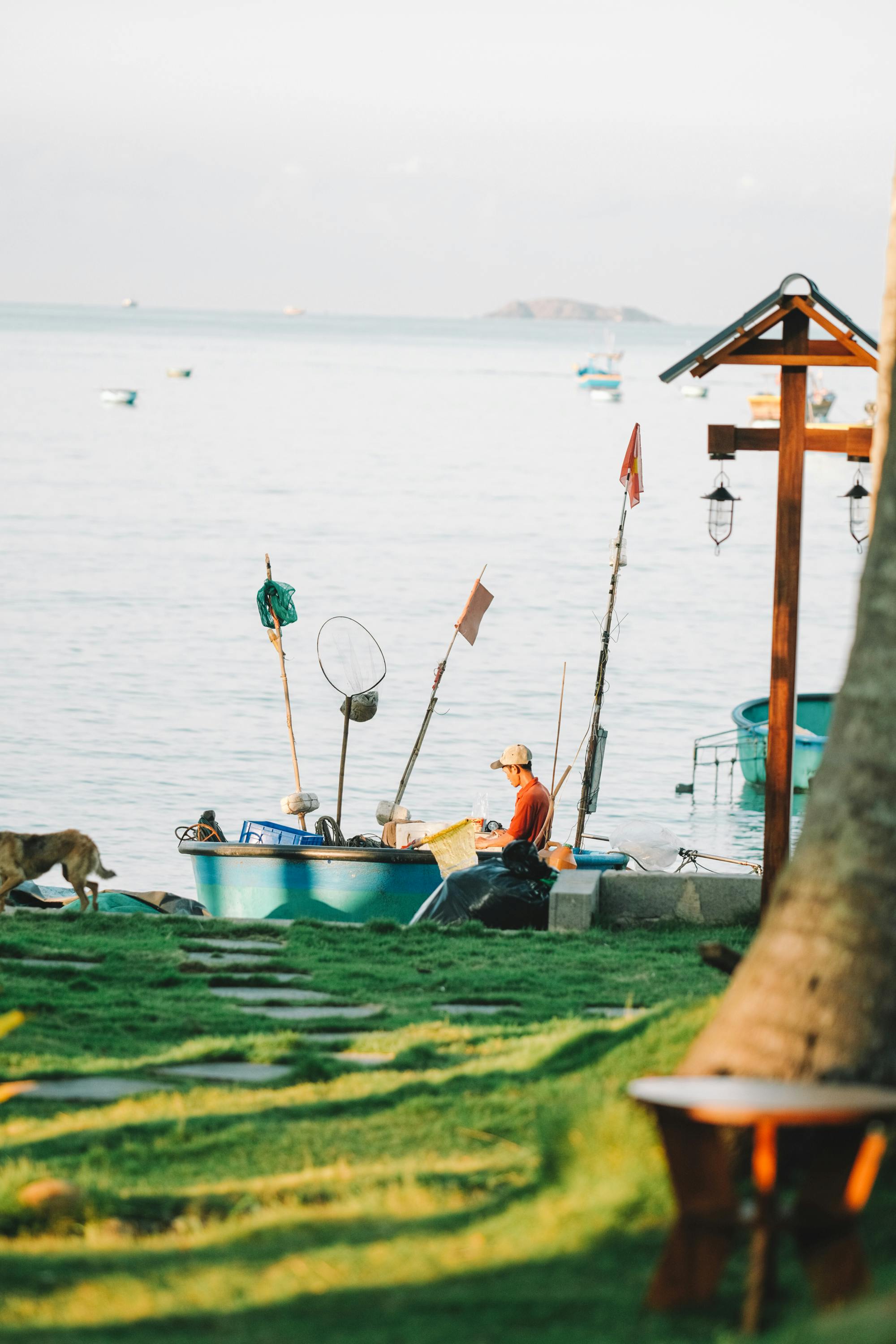 man sitting at the coast in front of a fishing boat