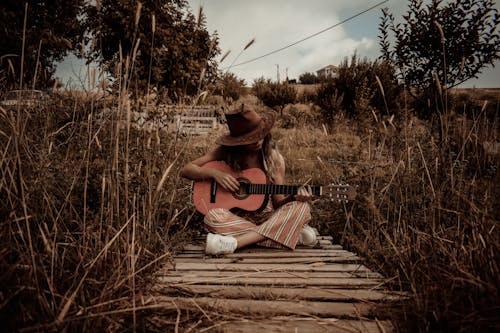 Gratis Wanita Memegang Gitar Duduk Di Dermaga Foto Stok