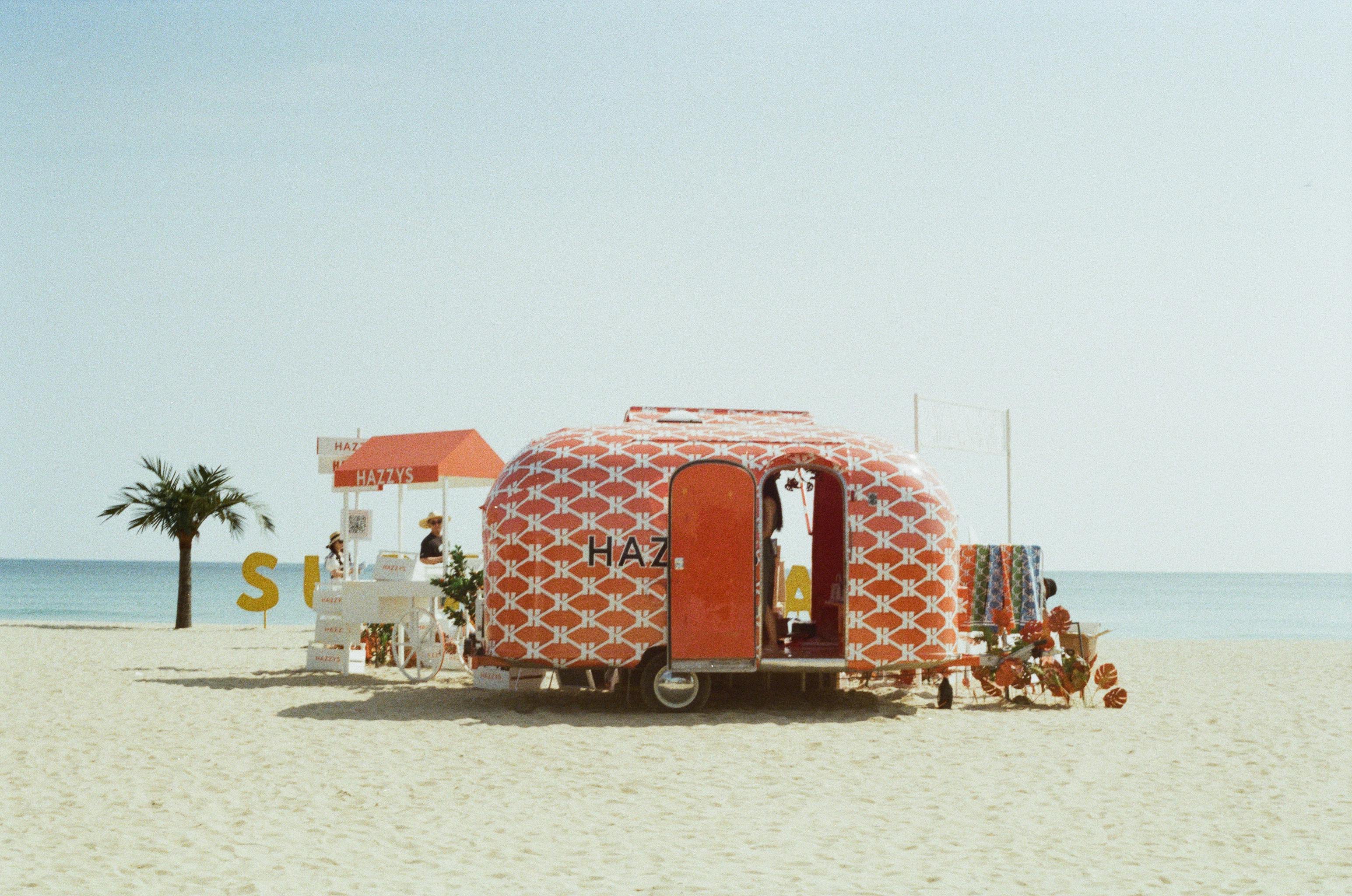 A vibrant retro trailer on sandy Yangyang beach, ideal for summer relaxation.
