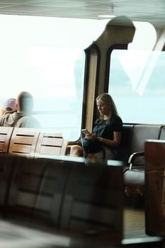 A woman reads peacefully by a large window in a transit lounge, captured in a reflective setting.