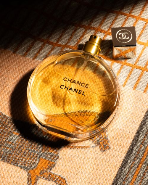 Free Elegant glass bottle of Chanel Chance fragrance with branded cap on textured fabric. Stock Photo