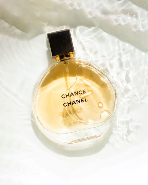 Free Chanel Chance perfume bottle with water reflections on a white background, showcasing elegance and luxury. Stock Photo