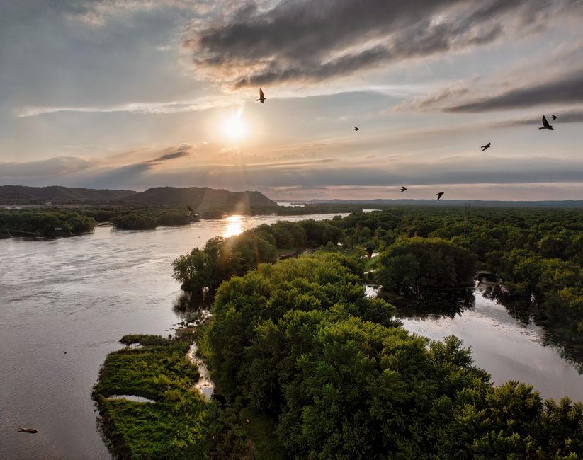 Captivating aerial view of the Mississippi River surrounded by lush greenery at sunset in Wabasha, MN.