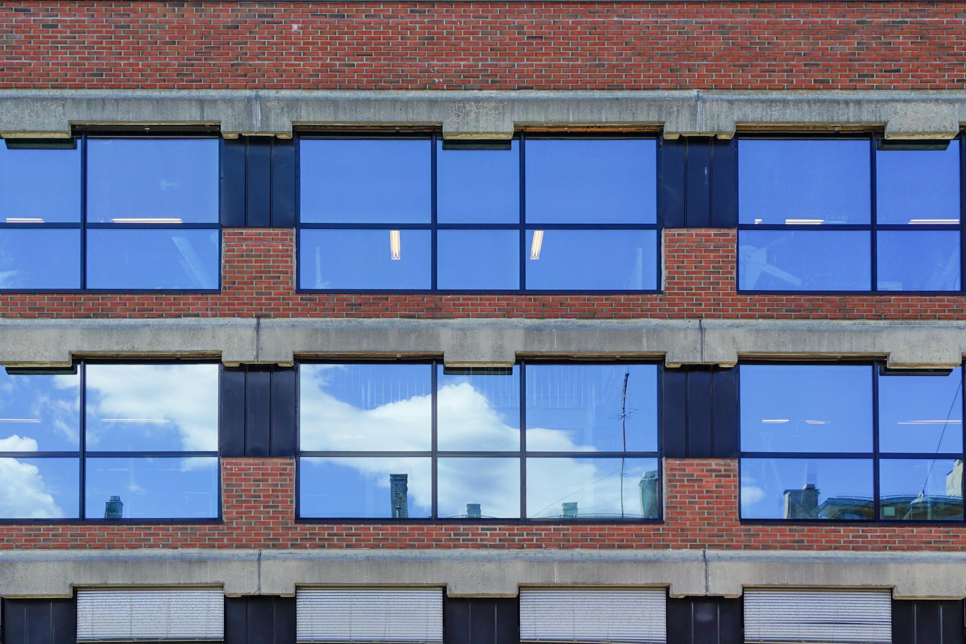 Brick building in Oslo with large reflective windows and clear blue sky reflections.