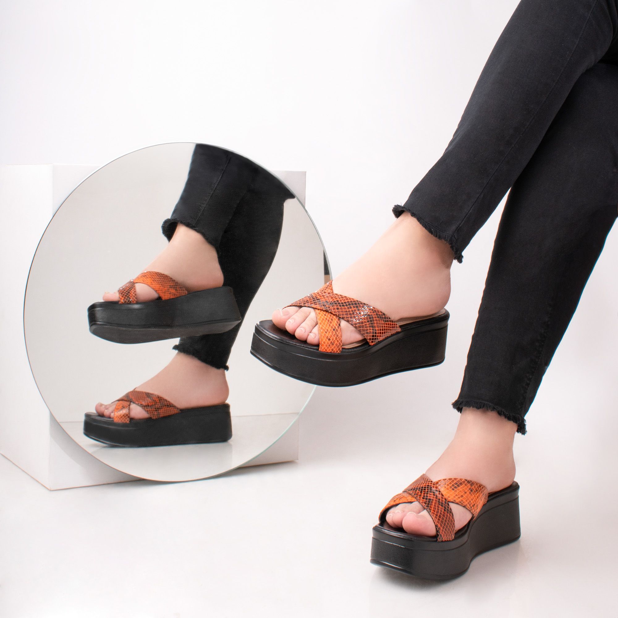 Chic platform sandals with a stylish animal print design, perfectly showcased with a mirror reflection.
