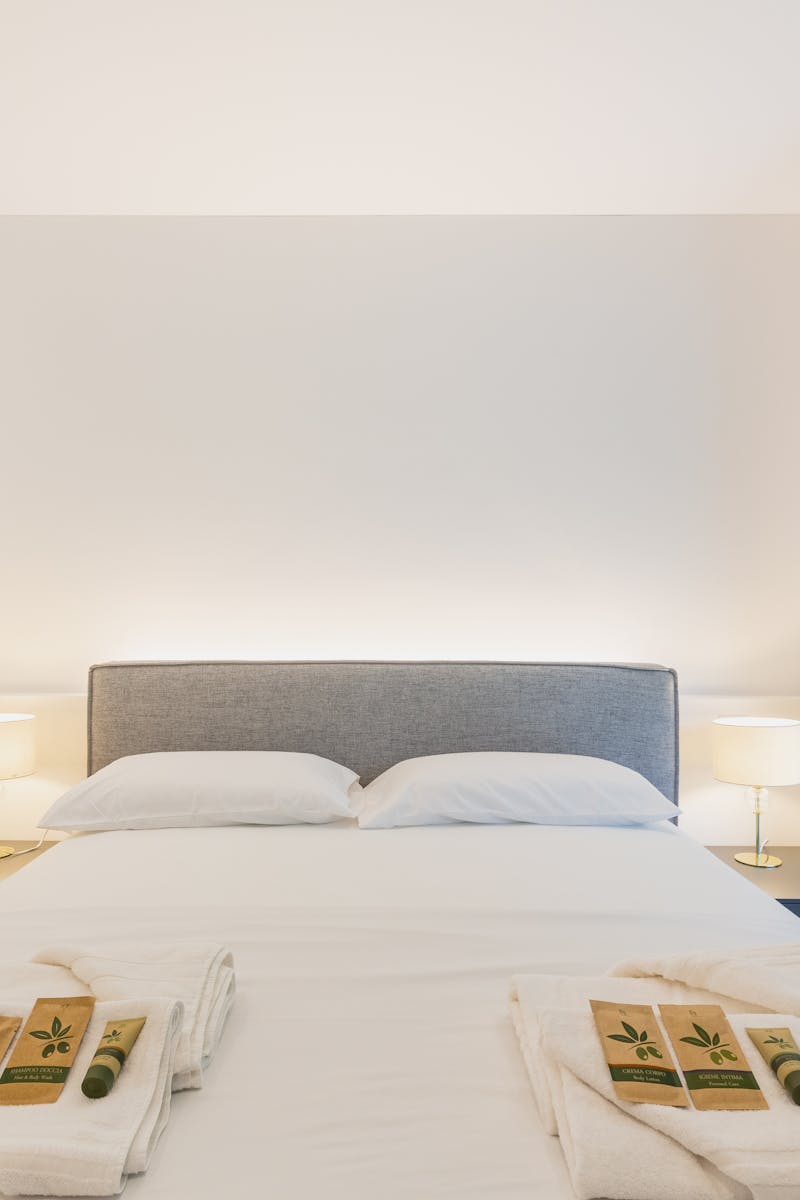 Modern minimalist bedroom with neutral tones, cozy bed, and balcony view; perfect for restful retreats.