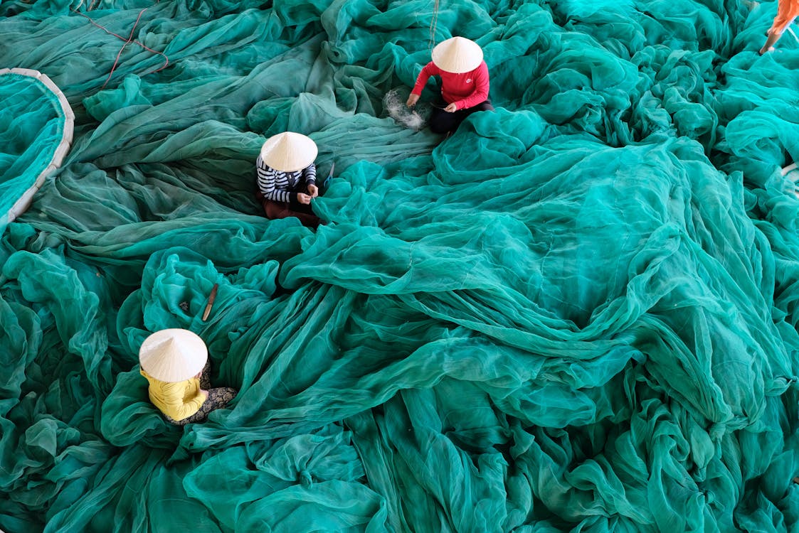 Three Person Sitting on Green Large Net