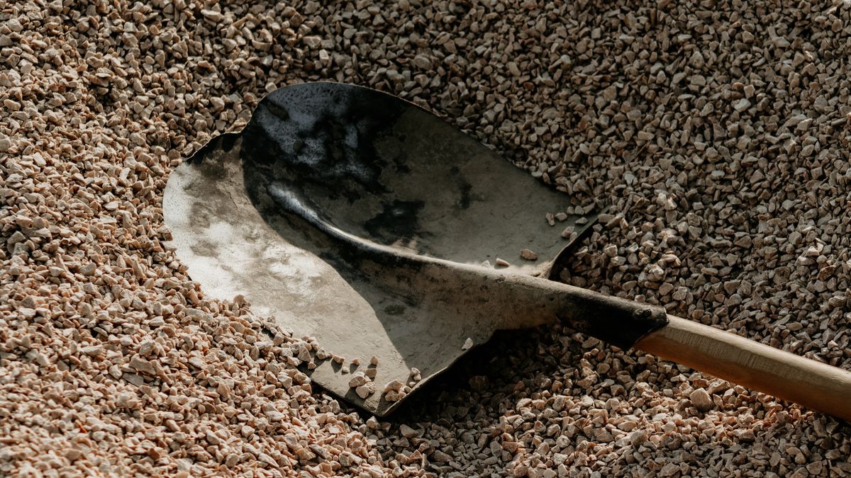 A shovel in a pile of small stones. A cubic yard of gravel weighs well over a ton.