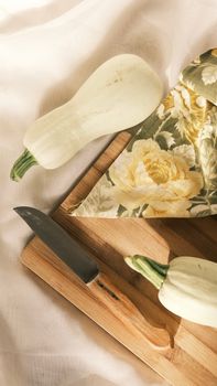 Fresh white squashes with a knife on a wooden cutting board, perfect for autumn recipes.