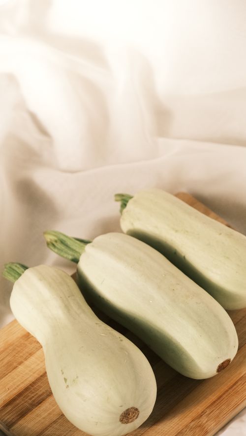 Free Three fresh white zucchinis displayed on a wooden cutting board, showcasing simplicity and freshness. Stock Photo
