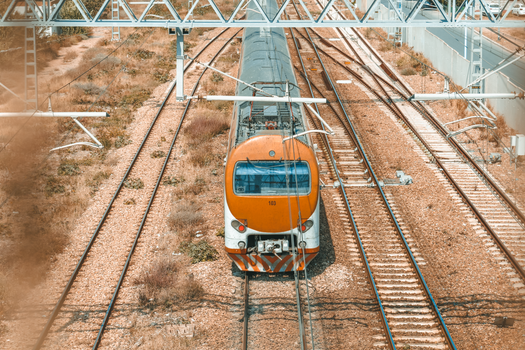 Aerial shot of an orange train on tracks in a rural setting, showcasing transportation and infrastructure.