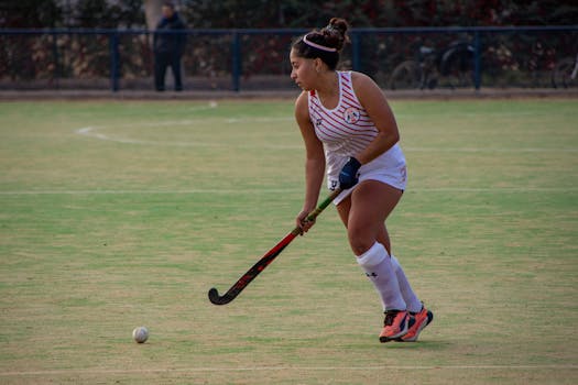 Female field hockey player in action on the field, demonstrating skill and focus.