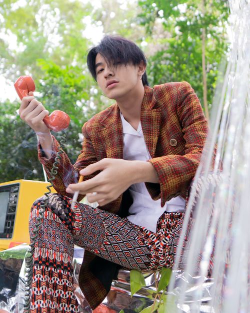 Free A fashionable Asian man poses outdoors with a vintage telephone, showcasing an artistic and retro style. Stock Photo