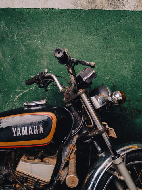 Free Close-up of a vintage Yamaha motorcycle parked against a green wall in Quepem, India. Stock Photo