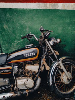 Classic Yamaha RX 135 motorbike parked against a vibrant green wall in Quepem, India.