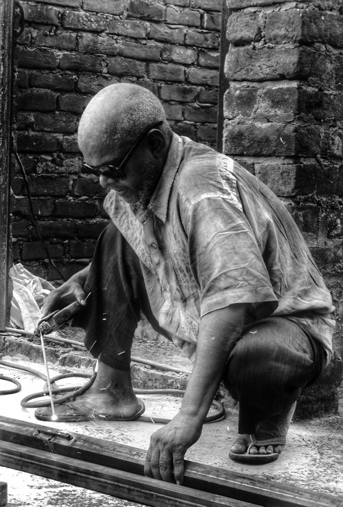 Free Elderly man engaged in metalworking, showcasing craftsmanship and dedication in a workshop. Stock Photo