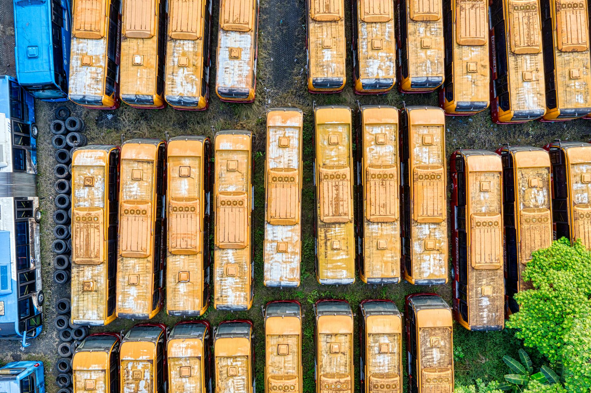 Top-down shot of numerous yellow buses parked in a lot, seen from above.