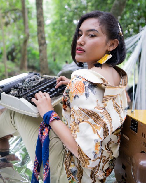 Free A fashionable woman using a vintage typewriter outdoors, embodying style and creativity. Stock Photo