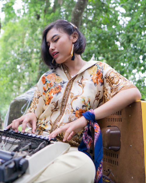 Free A fashionable woman uses a vintage typewriter in a natural outdoor setting, exuding style and elegance. Stock Photo