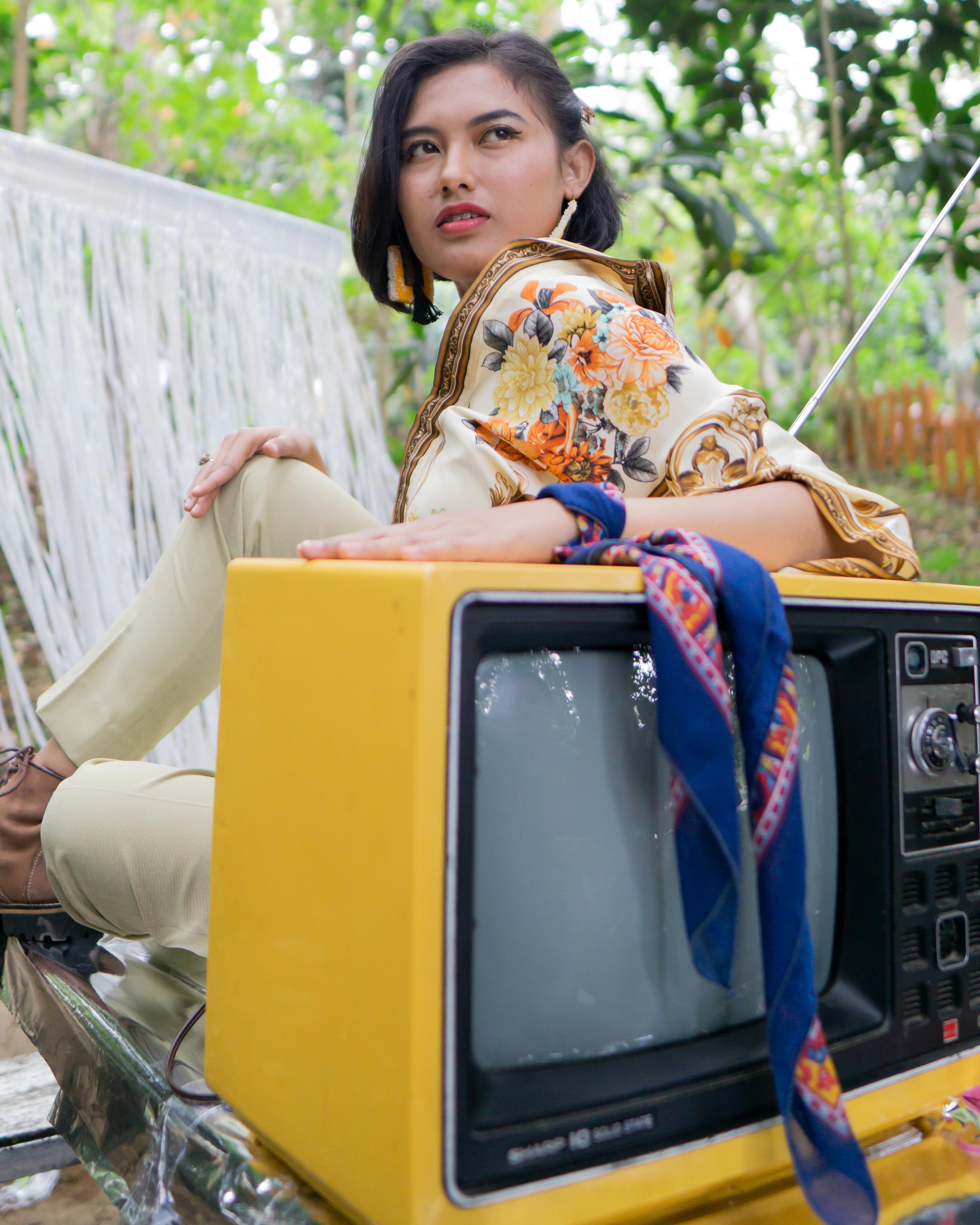 时尚的女人在户外与老式电视合影，展现风格与天赋