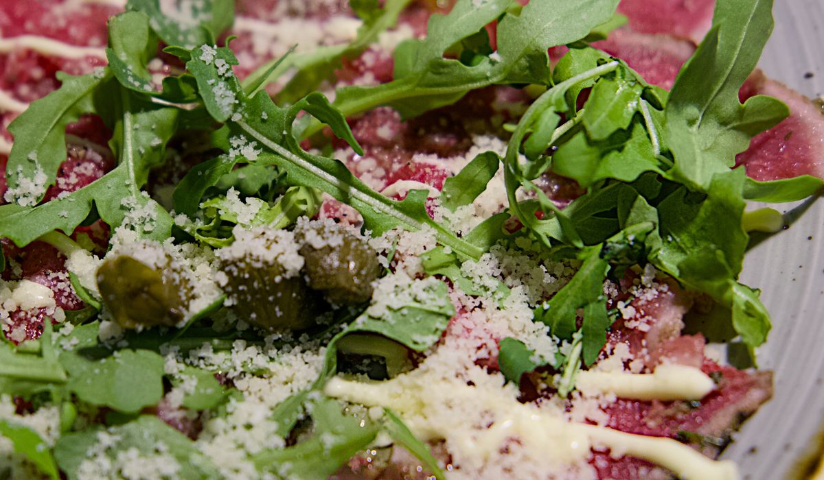 Thinly sliced cured meat plated with fresh lettuce for a classic Italian appetizer presentation