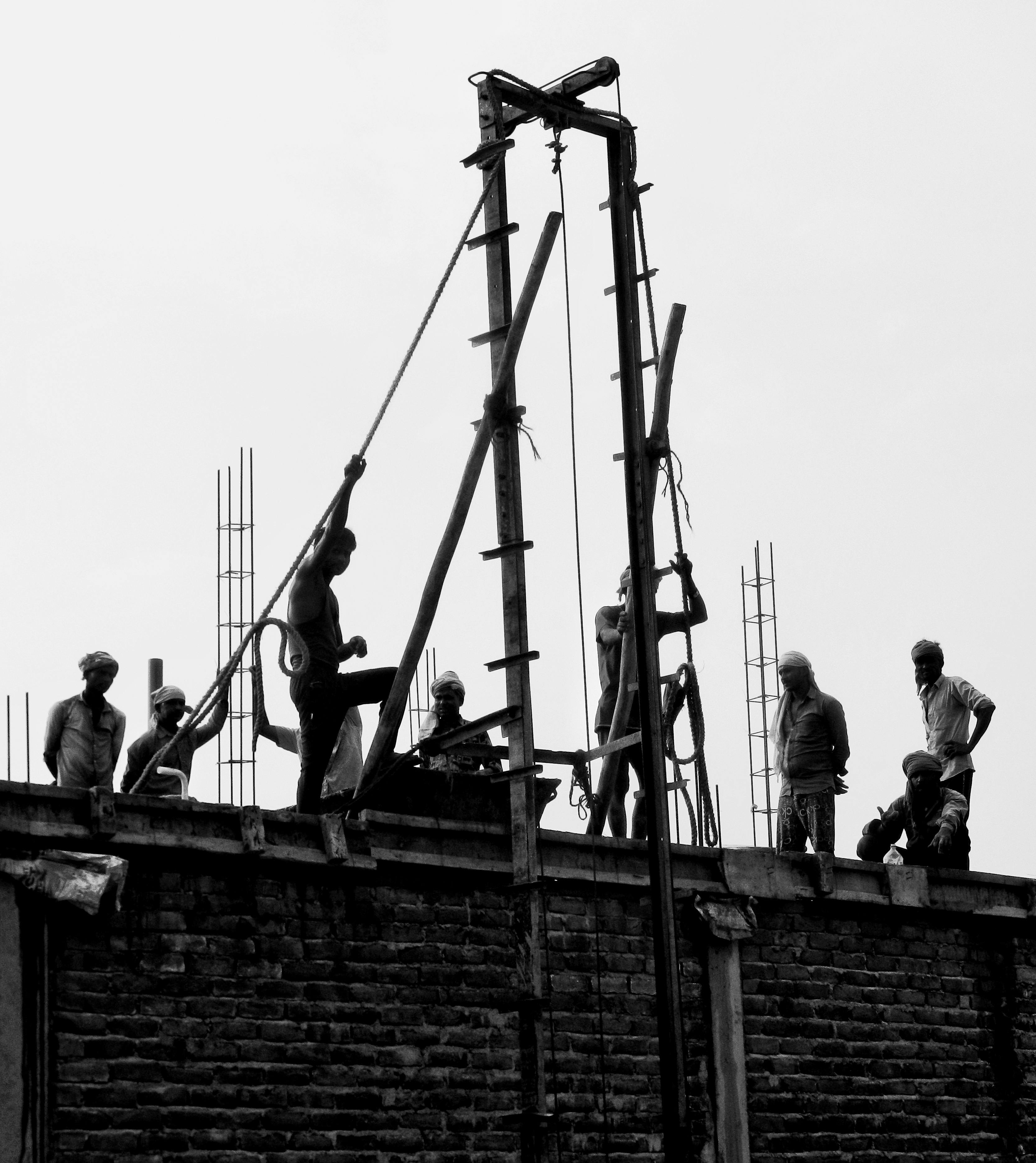 Silhouetted workers on a construction site rooftop emphasizing teamwork and determination.