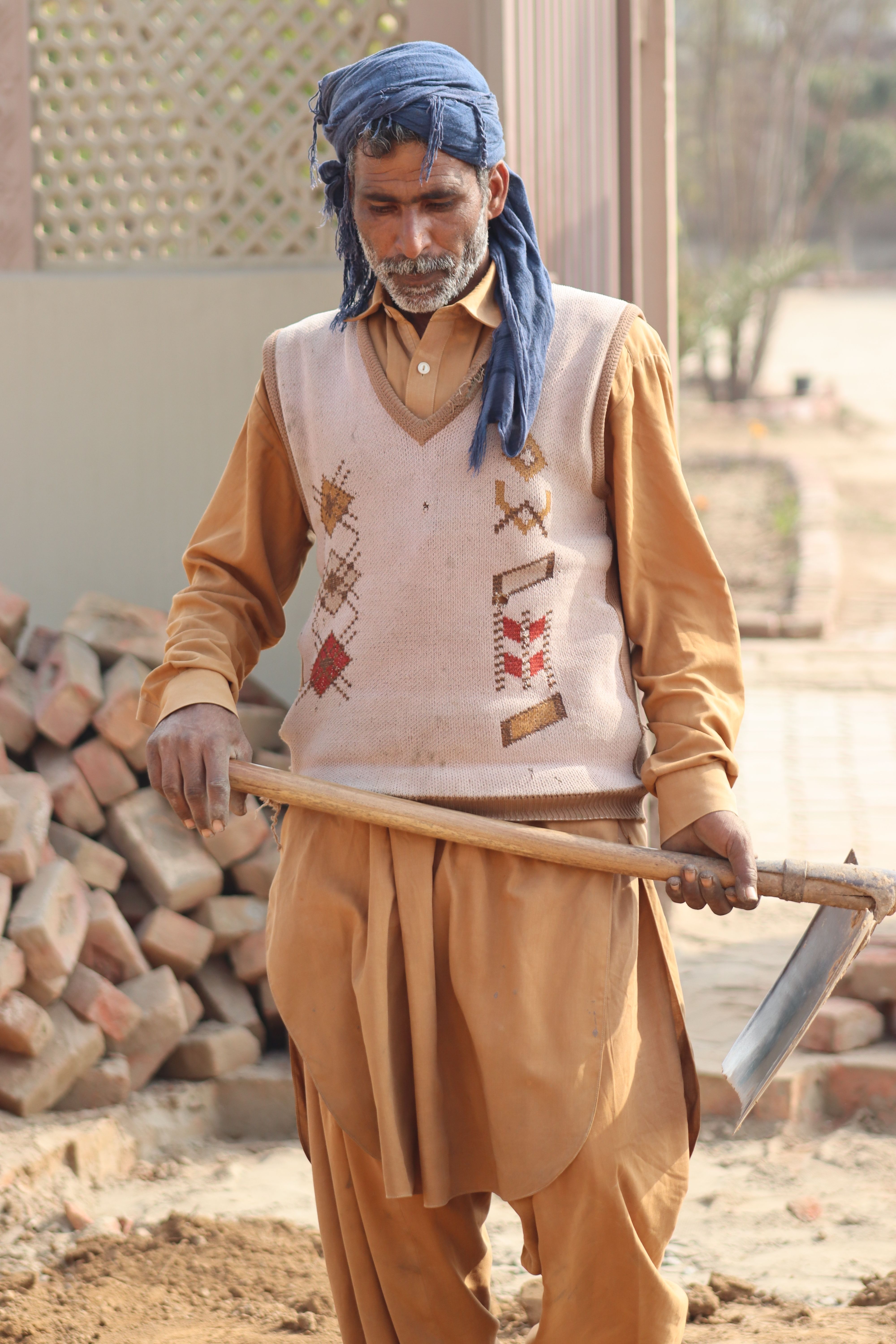 Portrait of a rural farmer holding a scythe and standing in a rustic setting, wearing traditional attire.