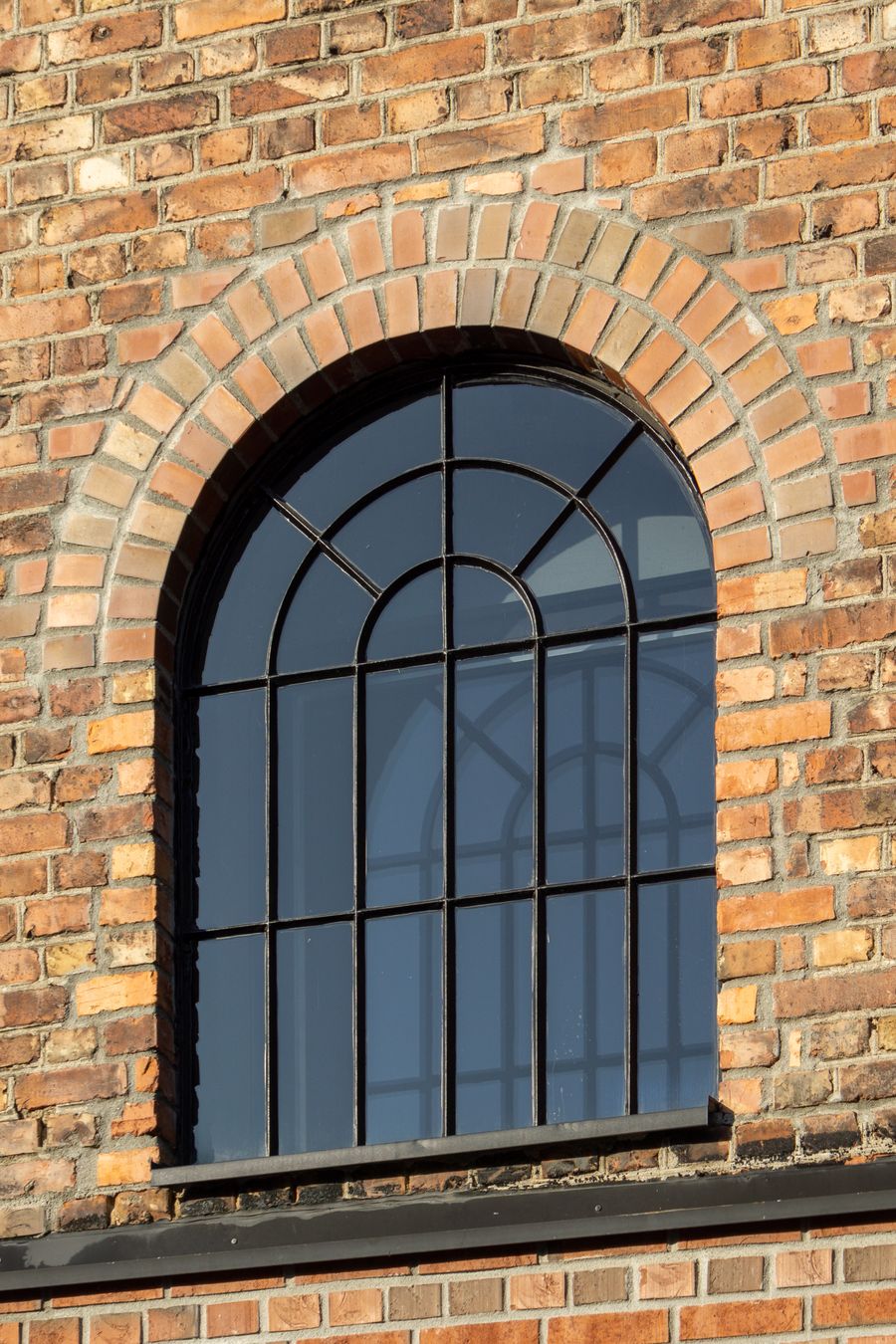 Historic brick wall with window framed in black, showing weathered mortar joints