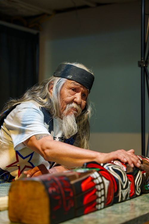 Free Elderly man creating indigenous wood art indoors, showcasing cultural heritage. Stock Photo