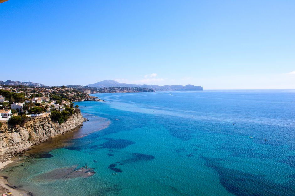 Scenic aerial view of Calp's stunning coastline with clear blue waters and cliffs under a bright blue sky.