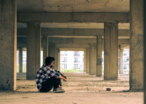 Man Sitting Under a Bridge