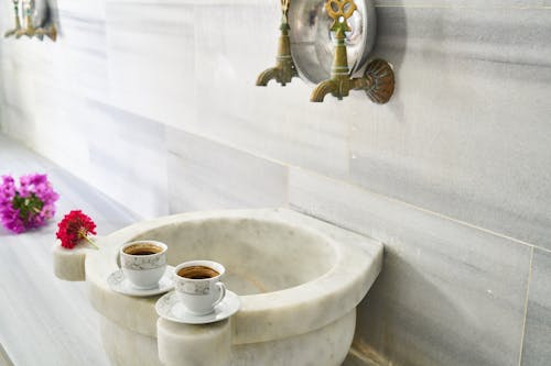 Two White Ceramic Teacups on Marble Sink