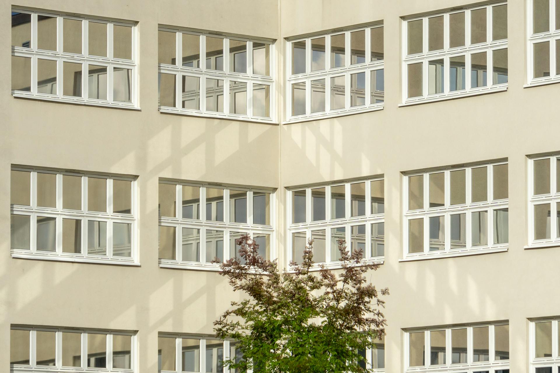 Urban building facade in Oslo with symmetrical windows and sunlight reflections.