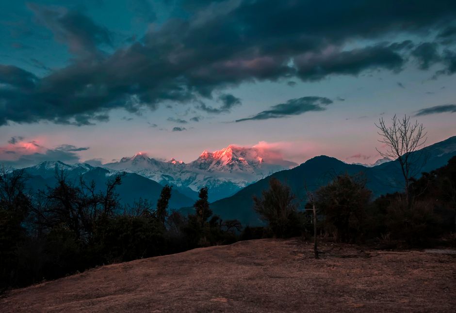 Breathtaking view of snowcapped mountains glowing under a twilight sky with rich cloud formations.