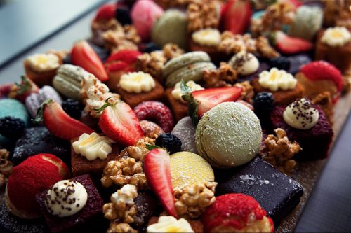 Free A vibrant assortment of desserts featuring macaroons, strawberries, and walnuts, ideal for food photography. Stock Photo