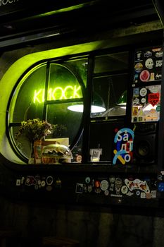 A vibrant coffee shop window with neon lights and an array of stickers, creating an urban night vibe.