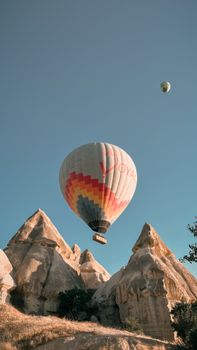 Colorful hot air balloon soaring over Cappadocia's unique rock formations at sunrise.